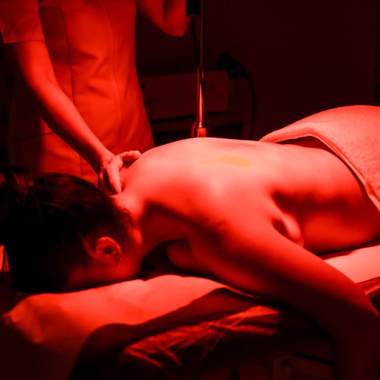 Chiropractic giving a heat massage to a woman lying down in stretcher in the clinic