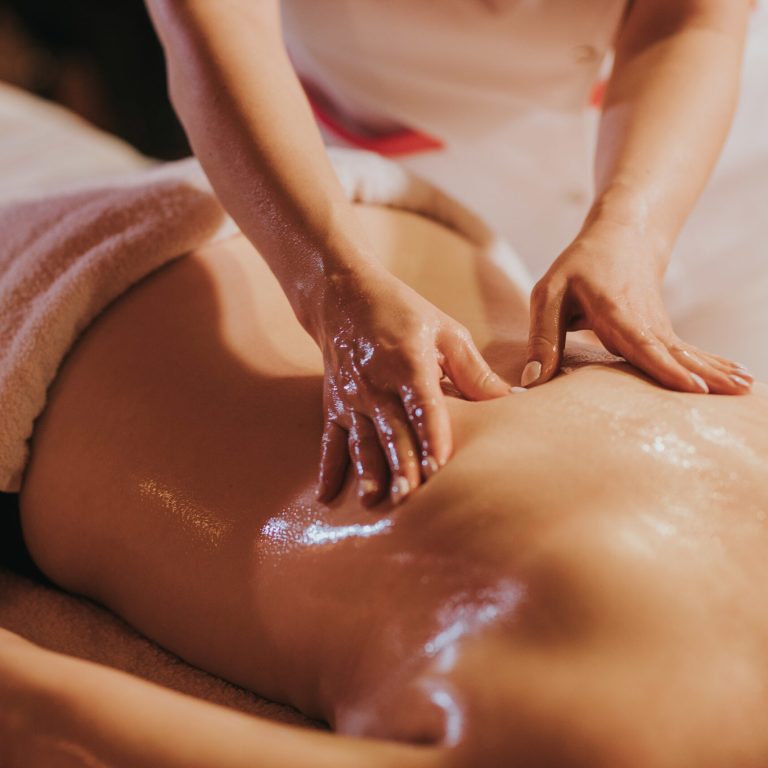 The woman getting massage treatment against back pain in the spa salon